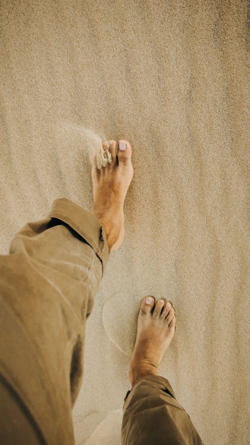 barefoot person walking on a sandy beach