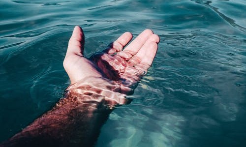 hand reaching out on a body of water