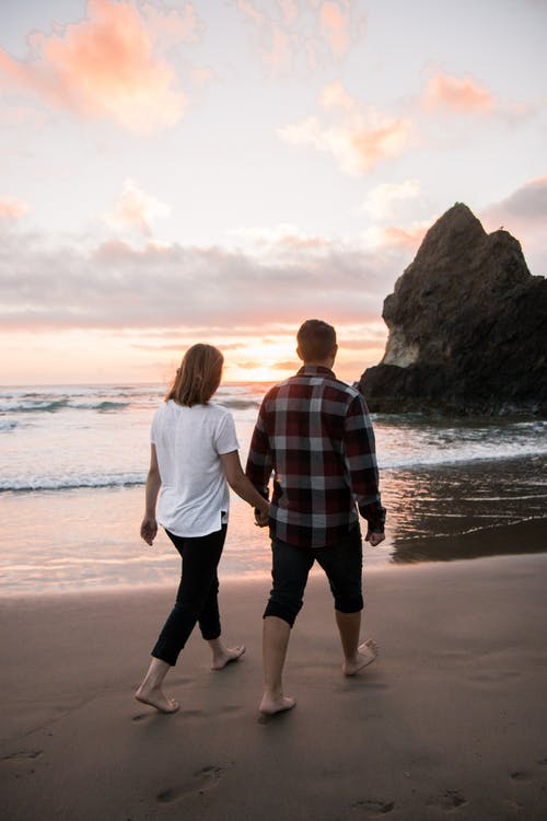 couple holding hands walking on the beach