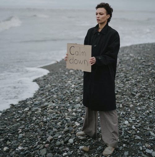 woman holding sign on rocky shore