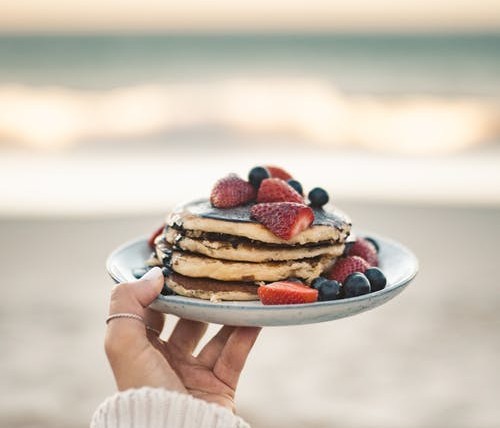 person holding a plate of pancakes