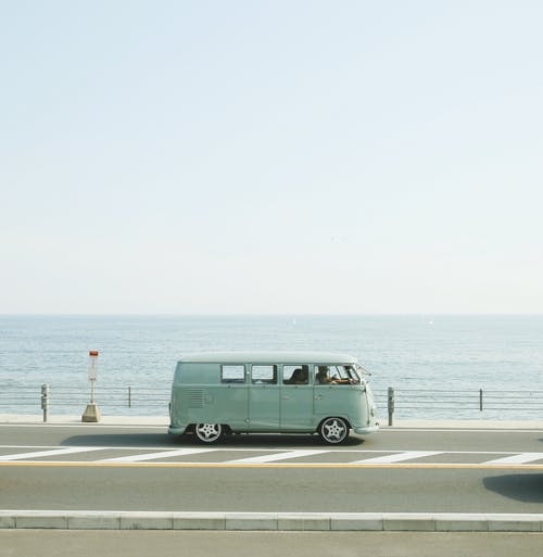 van parked on the road beside handrail and ocean